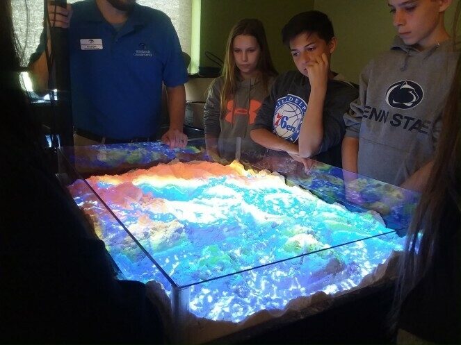 Children gathered around a watershed model.