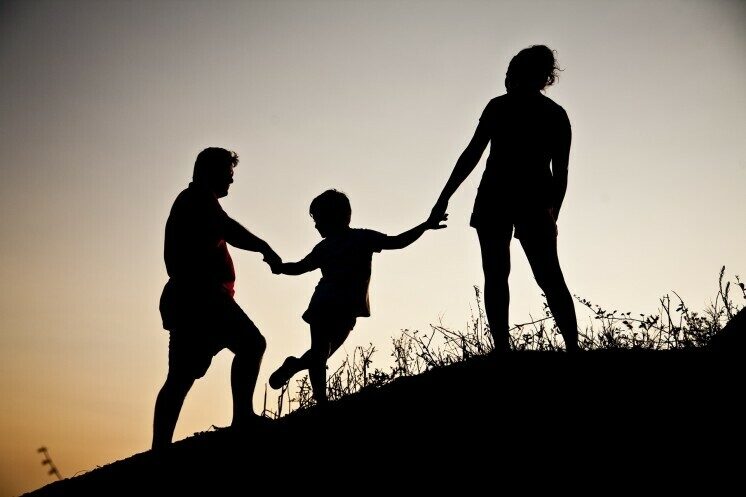 Silhouette of family climbing a hill.