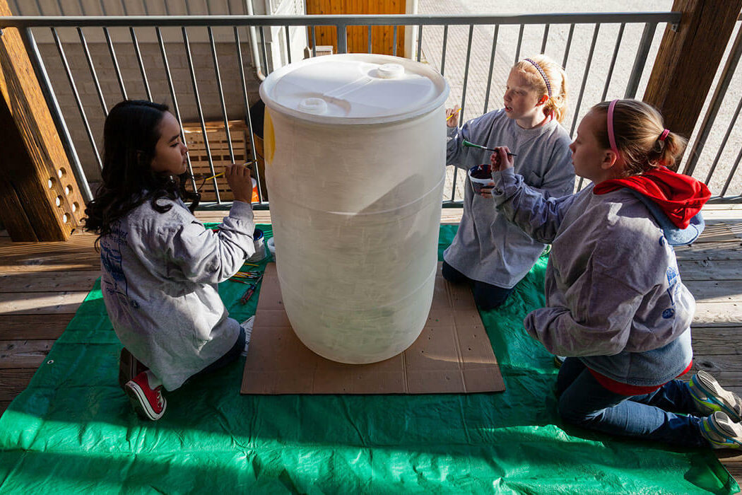 Students paint a rain barrel