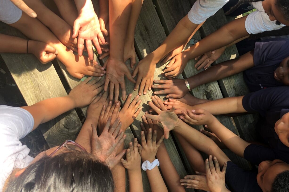 A group of students show off their dirty hands in a circle.