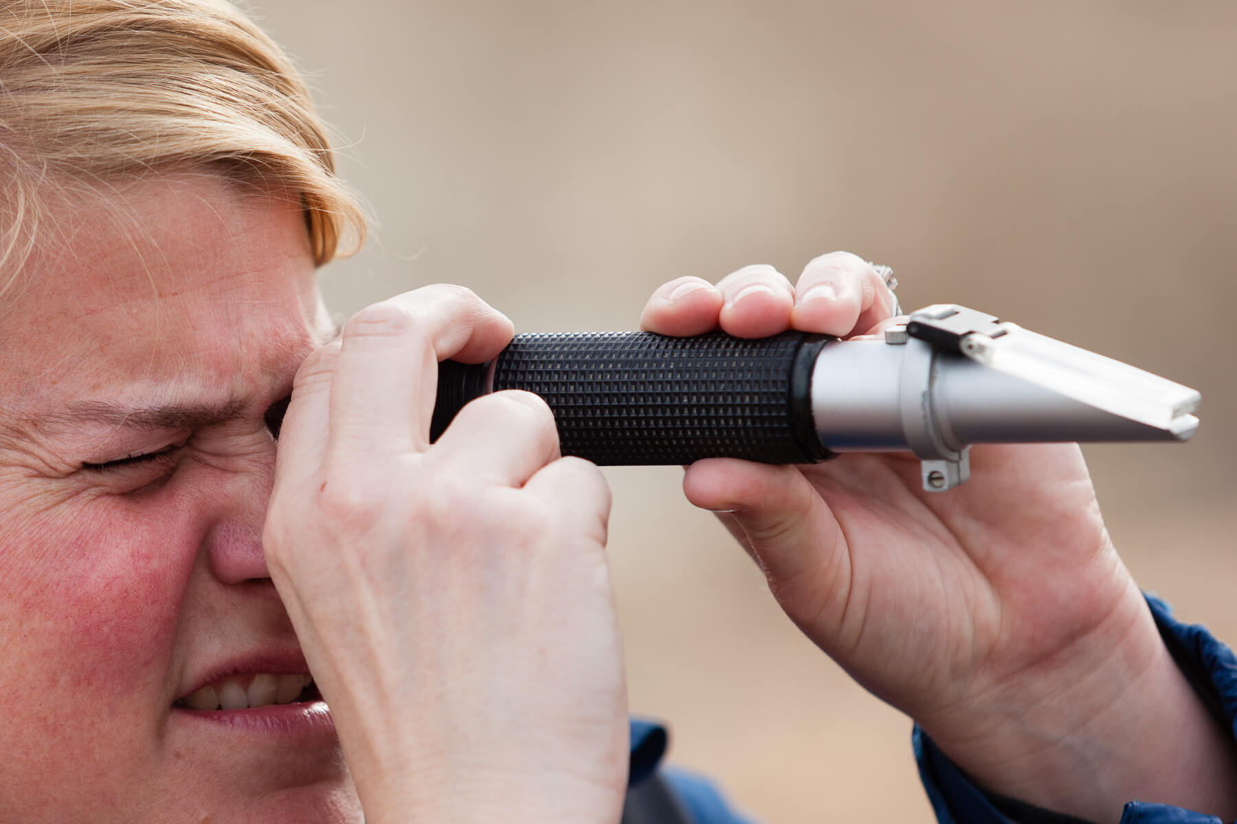 An image of a person looking through a refractometer viewfinder